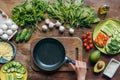 flat lay with female hand holding empty frying pan and various ingredients