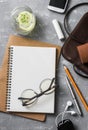 Flat lay female office desk with notepad, tablet, leather bag, glasses, earphones, phone, lipstick and a glass of refreshing lemon