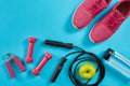 Flat lay of female sport equipments, jump rope, bottle of water and pink sneakers on blue background Royalty Free Stock Photo