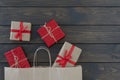 Flat lay of four gift boxes tired with ribbon, new year stuff look out from paper bag on wooden background, copyspace. Royalty Free Stock Photo