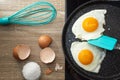 Flat lay of fried eggs with spatula in a frying pan, salt and eggshell on the table