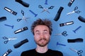 Flat lay funny face of bearded disheveled man and barber grooming hairdresser tools accessories on blue background. Barber shop,