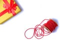 Flat lay with a gold gift box with a red bow and a red strass chain for decorating a Christmas tree or gifts