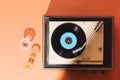 Flat lay gramophone record player from sixties. Turntable for single vinyl on orange background. Two cocktail glasses, party vibe