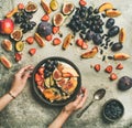 Flat-lay of Greek yogurt, fruit, chia seeds bowl in hands Royalty Free Stock Photo