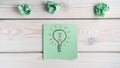 Flat lay of green sticker note with light bulb and red exclamation mark inside near crumpled notes. Idea, creative work. Royalty Free Stock Photo