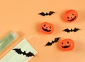 Flat lay of Halloween pumpkin , black paper bats,medical mask and alcohol sanitizer gel on orange background. Halloween , COVID-