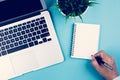 Flat lay, hand of businessman writing on notebook with Laptop computer and plant and pen on desk in office. Royalty Free Stock Photo