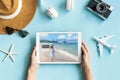 Flat lay of hands holding tablet and travel accessories on blue color background. Travel, summer vacation concept. Copy space for Royalty Free Stock Photo