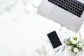 Flat lay home office desk. Female workspace with laptop computer, blank screen smartphone, flowers bouquet, cosmetic. Top view Royalty Free Stock Photo