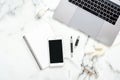 Flat lay home office desk. Female workspace with laptop computer, dry flowers, paper notepad, smartphone on marble background. Top