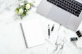 Flat lay home office desk. Female workspace with laptop computer, white roses flowers bouquet, accessories, diary on white marble