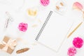 Flat lay home office desk. Top view blank paper notepad, pink rose flower buds, petals, female accessories, gift box on white Royalty Free Stock Photo