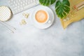 Flat lay home office feminine table with coffee cup, golden accessories, computer keyboard and tropical leaves on grey background Royalty Free Stock Photo