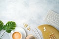 Flat lay home office feminine table with coffee cup, golden accessories, computer keyboard and tropical leaves on grey background