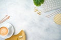 Flat lay home office feminine table with coffee cup, golden accessories, computer keyboard and tropical leaves on grey background