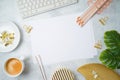 Flat lay home office feminine table with paper, golden accessories, computer keyboard and tropical leaves on grey background. Top