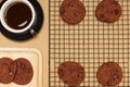 Flat lay of homemade sweets, Chocolate cookies on rack and stack in wooden tray with hot coffee Royalty Free Stock Photo