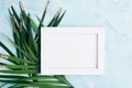 Flat lay horizontal photo frame mock up with green and gold palm leaves on blue background. Travel concept Royalty Free Stock Photo