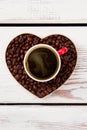 Flat lay hot coffee cup above heart made of coffee beans. Royalty Free Stock Photo