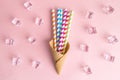 Flat lay of ice cream cone and multicolored drinking straws with ice cubes sweet food and drink abstract on rose