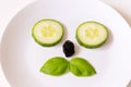 Flat lay image of funny cat-like face made with cucumber eyes, basil moustaches and dried fruit nose Royalty Free Stock Photo