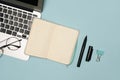 Flat lay image showing laptop, lined notebook, and office supplies on a blue background Royalty Free Stock Photo