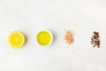 Flat lay of ingredients for vinaigrette sauce. Lemon, olive oil, Himalayan salt red black white pepper on white stone background.