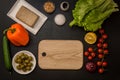 Flat lay. Italian food. Brown wooden cutting board surrounded by plant based ingredients for vegan greek salad. Copy space