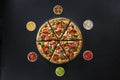 Flat lay of italian pizza and fresh ingredients around on dark surface top view
