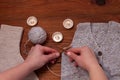 Flat lay of knitted vest, socks, candles, female hands hold knitting needles, yarn on wooden background. Cozy flatlay