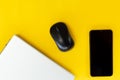 Flat lay of laptop, black smartphone with empty screen, and wireless mouse on vibrant yellow background Royalty Free Stock Photo