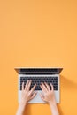 Flat lay of laptop, coffee and notebook on yellow background. Female hands typing on keyboard Royalty Free Stock Photo