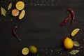 flat lay with lemon and lime pieces, spices, chili peppers and bay leaves on black tabletop