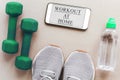 gray sneakers, green dumbbells, bottle of water, and a smartphone