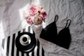 Flat lay. Top view black lace lingerie. Beauty blog concept. Bouquet of roses and pions, coffee on white bed background Royalty Free Stock Photo