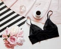 Flat lay. Top view black lace lingerie. Beauty blog concept. Bouquet of roses and pions, coffee on white bed background Royalty Free Stock Photo