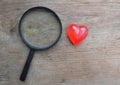 magnifying glass and decorative red hearts isolated on a brown wooden background minimalist trend.valentines day concept