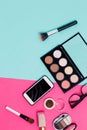 Flat lay of makeup products smartphone and women glasses blue and pink background, top view