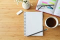 Flat lay mock-up of a blank spiral notebook on a wooden desk with organizer, coffee, glasses and flowers, copy space, selected