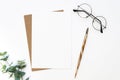 Flat lay Mockup blank Card with a calligraphy pen, glasses, and flower on a white table. Copy space Royalty Free Stock Photo