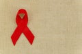 Flat lay mockup Red ribbon 1st September World AIDS day symbol, frame with copy space for text on sackcloth background Royalty Free Stock Photo