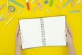 Flat lay mockup student`s hands holds blank notepad. Top view framed with tationery and chalks Royalty Free Stock Photo