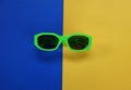 Modern green sunglasses isolate on a yellow and blue  background.Traveler and summer accessories Royalty Free Stock Photo