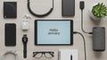 Flat lay of modern tech gadgets and accessories on a light background with Hello January on a tablet screen Royalty Free Stock Photo
