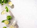 Flat lay of mojito cocktail with lime, fresh mint and ice, bottle with mojito on white texture background close up. Summer Royalty Free Stock Photo