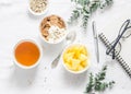 Flat lay morning breakfast inspiration - greek yogurt with whole grain cereals, tea, pineapple and notepad, glasses on a light bac