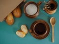 Breakfast in earthenware served with a wooden spoon, French baguette on a green background. Earthenware with handmade