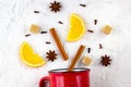 Flat lay of mulled wine ingredients. Cinnamon, orange, cardamom, clove, anise star and cup on white