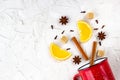 Flat lay of mulled wine ingredients. Cinnamon, orange, cardamom, clove, anise star and cup on white